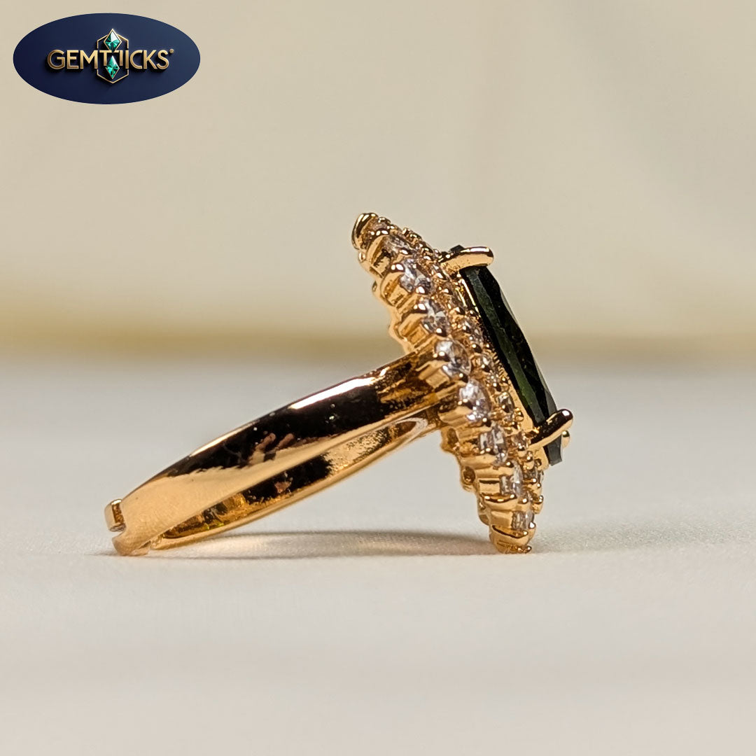 Gold ring with green gemstone and diamonds on a beige background