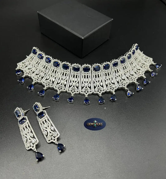 Jewelry set with necklace and earrings featuring blue stones on a dark surface.