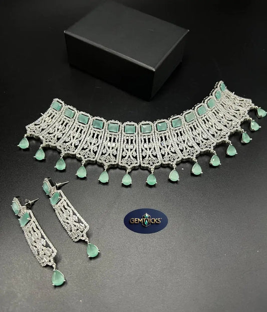 Jewelry set with necklace and earrings on a dark surface, featuring the Gemticks brand.